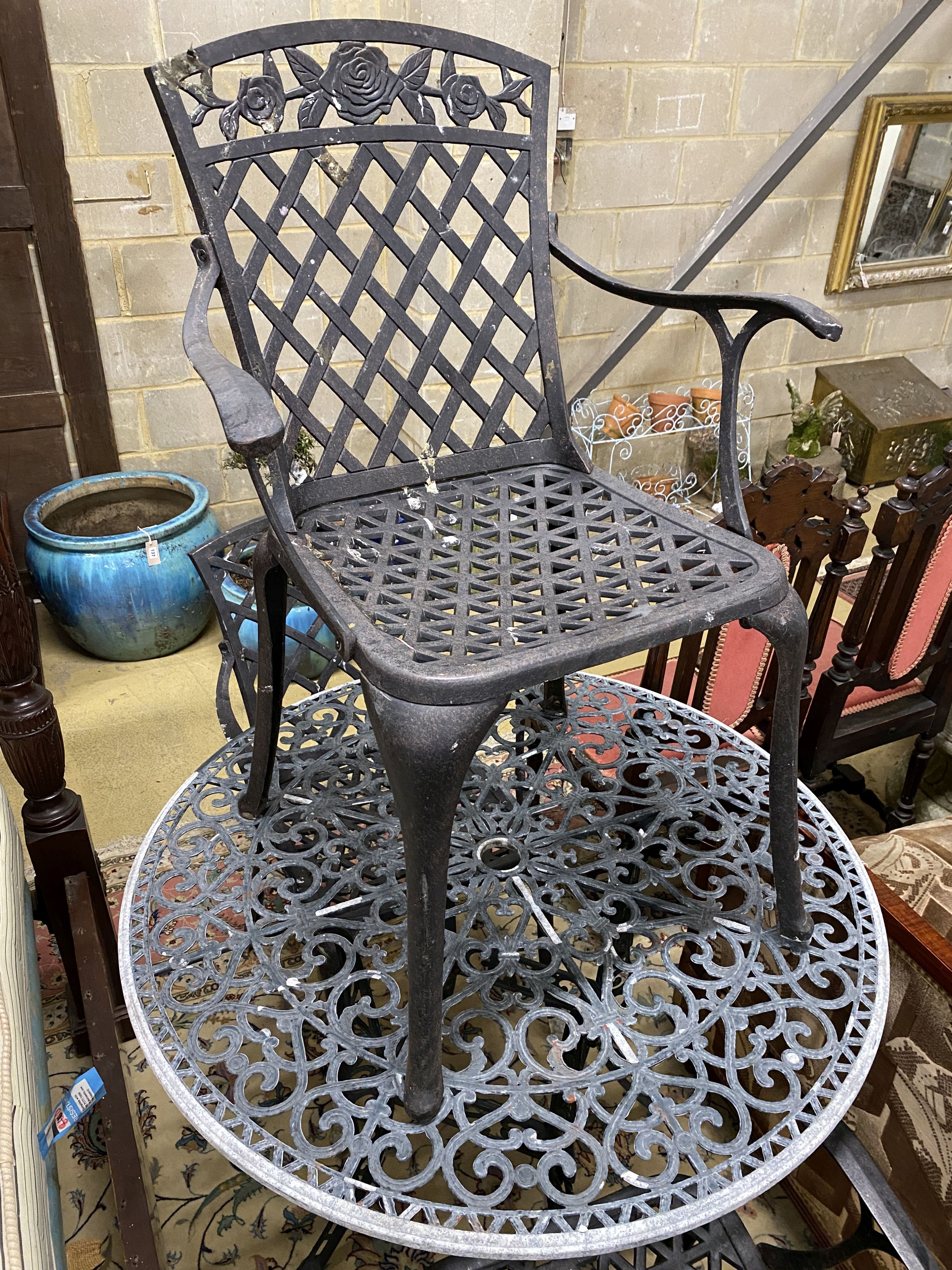 A circular painted aluminium garden table and three elbow chairs